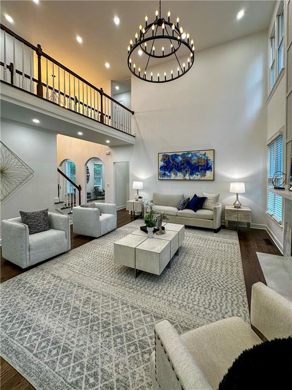 365 Morning Dew Cir, Roswell, GA 30075 - living room with a towering ceiling, wood finished floors, stairway, a chandelier, and baseboards