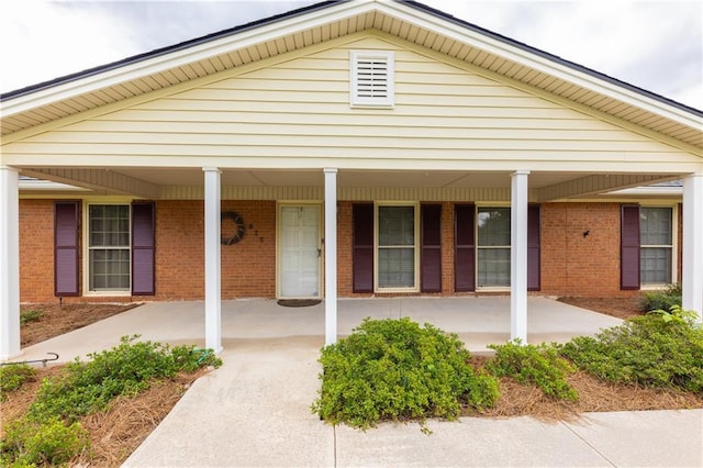 entrance to property featuring brick siding and a porch