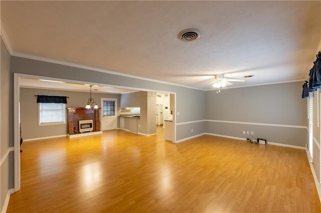 unfurnished living room with ceiling fan, a fireplace, light wood-style flooring, baseboards, and crown molding