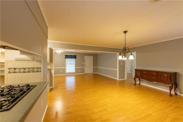 unfurnished dining area with ornamental molding, light wood-style flooring, baseboards, and a chandelier