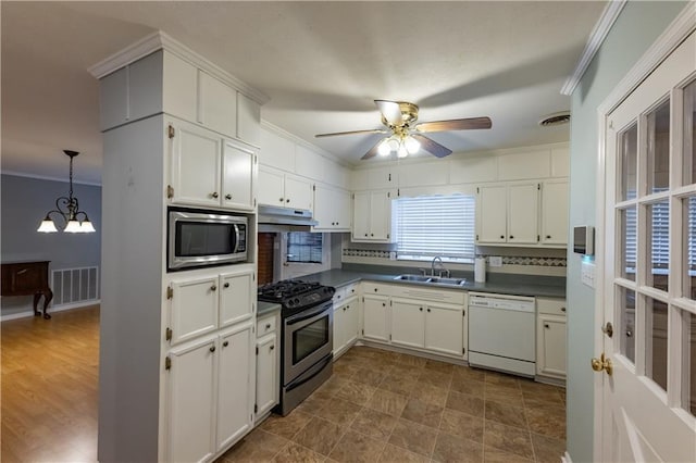 kitchen featuring stainless steel appliances, a sink, under cabinet range hood, crown molding, and dark countertops