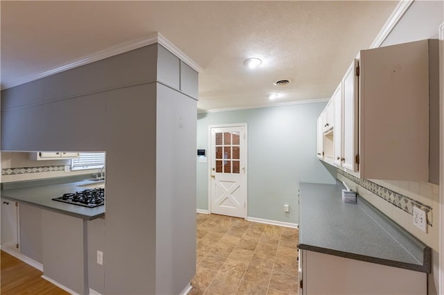 kitchen featuring gas cooktop, tasteful backsplash, dark countertops, crown molding, and baseboards