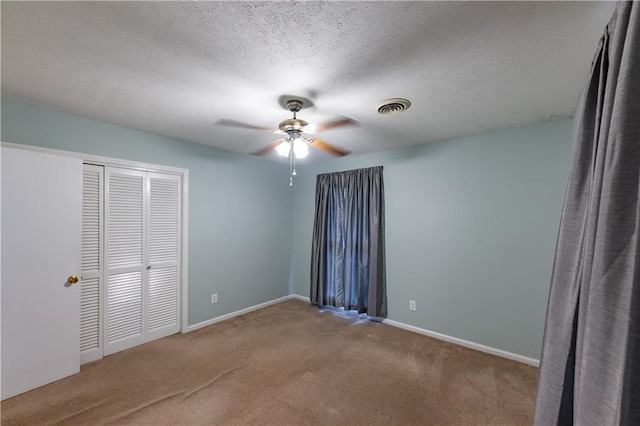 unfurnished bedroom with carpet, a closet, baseboards, a textured ceiling, and ceiling fan