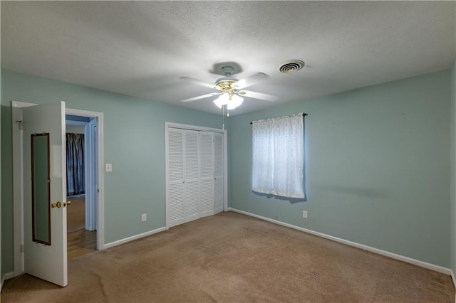 unfurnished bedroom featuring carpet, a closet, baseboards, a textured ceiling, and a ceiling fan