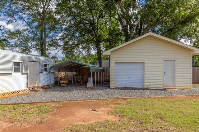detached garage with driveway, a detached carport, and fence