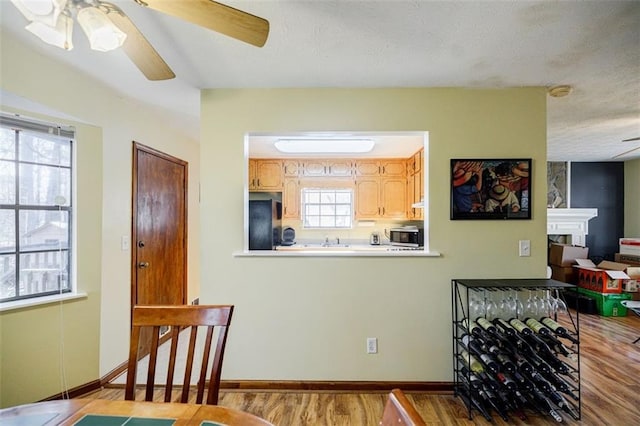 kitchen with black fridge, light brown cabinetry, ceiling fan, and light hardwood / wood-style flooring