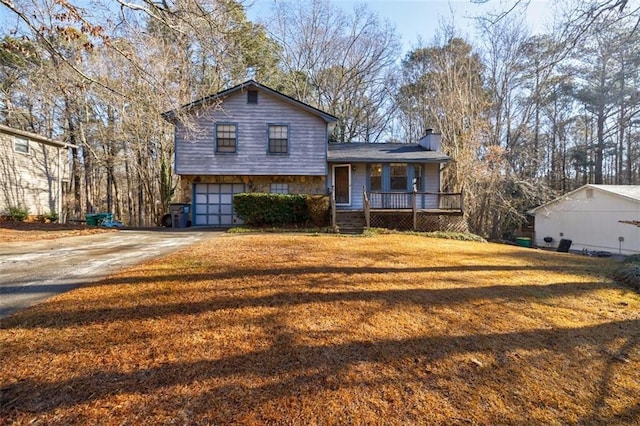 split level home with a garage, covered porch, and a front lawn