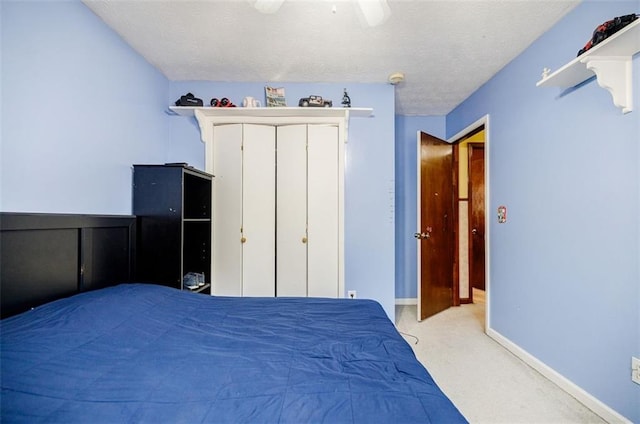 carpeted bedroom featuring ceiling fan and a textured ceiling