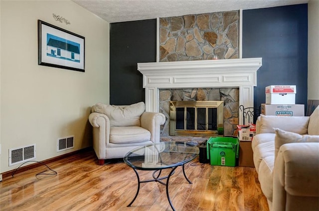 living area with hardwood / wood-style floors, a textured ceiling, and a fireplace