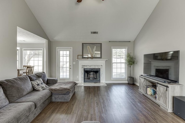 living room featuring ceiling fan, dark hardwood / wood-style flooring, a premium fireplace, and vaulted ceiling