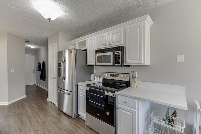 kitchen with a textured ceiling, light wood-type flooring, white cabinetry, and stainless steel appliances