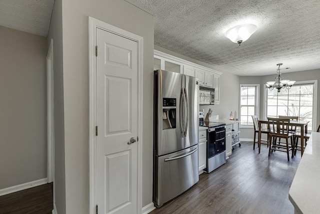 kitchen featuring dark hardwood / wood-style flooring, stainless steel appliances, a notable chandelier, white cabinets, and hanging light fixtures