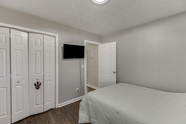 bedroom with a textured ceiling, dark hardwood / wood-style floors, and a closet