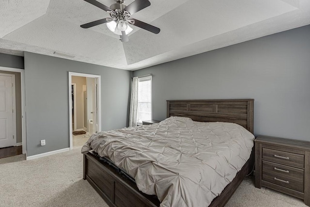 carpeted bedroom featuring ceiling fan, a raised ceiling, a textured ceiling, and ensuite bath