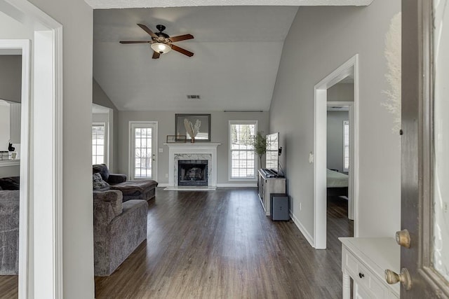 living room with ceiling fan, dark hardwood / wood-style flooring, a premium fireplace, and vaulted ceiling