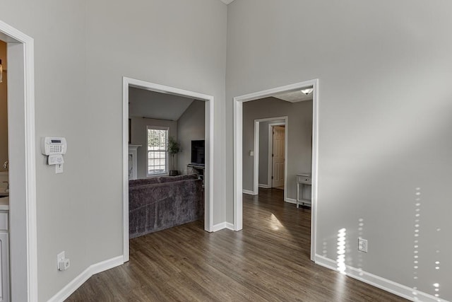 hall with lofted ceiling and dark wood-type flooring