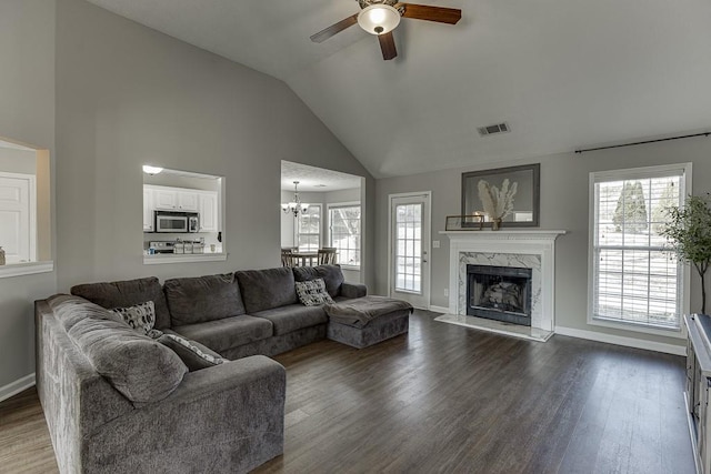 living room with dark hardwood / wood-style floors, lofted ceiling, ceiling fan with notable chandelier, and a high end fireplace