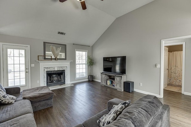 living room with a high end fireplace, wood-type flooring, vaulted ceiling, and ceiling fan