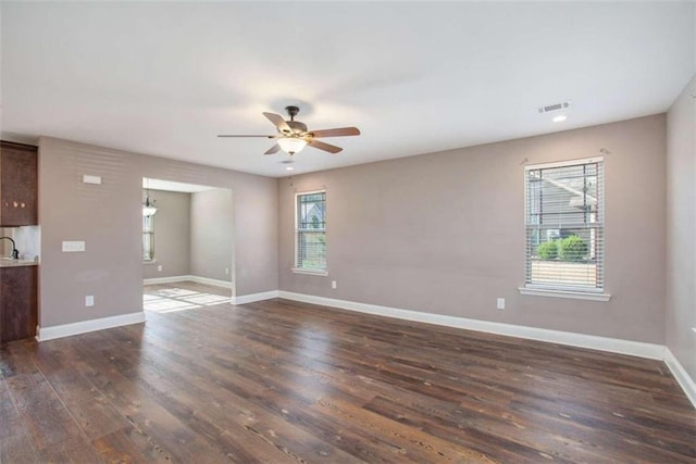 spare room featuring dark wood-type flooring, ceiling fan, and a wealth of natural light