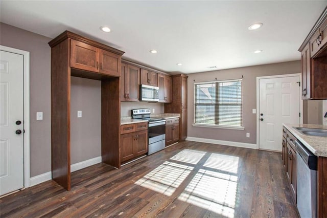 kitchen featuring appliances with stainless steel finishes, dark hardwood / wood-style flooring, sink, and light stone counters