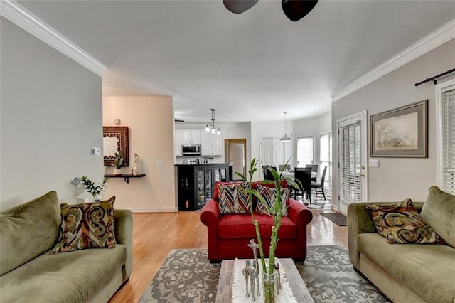 living room featuring ceiling fan with notable chandelier, crown molding, and light hardwood / wood-style flooring