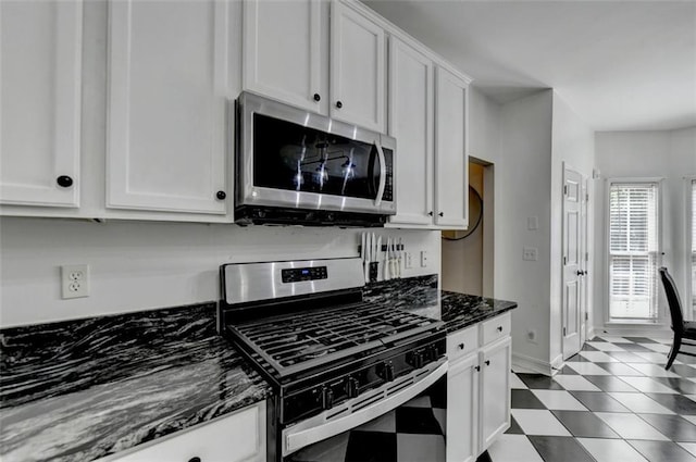 kitchen featuring white cabinets, appliances with stainless steel finishes, and dark stone counters