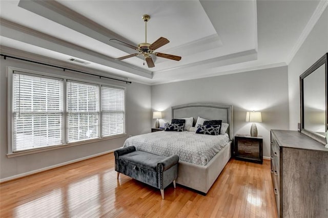 bedroom featuring ceiling fan, a raised ceiling, wood-type flooring, and ornamental molding