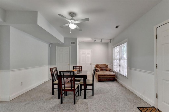 carpeted dining room with rail lighting and ceiling fan