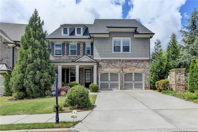 craftsman inspired home with driveway, covered porch, brick siding, an attached garage, and a front yard