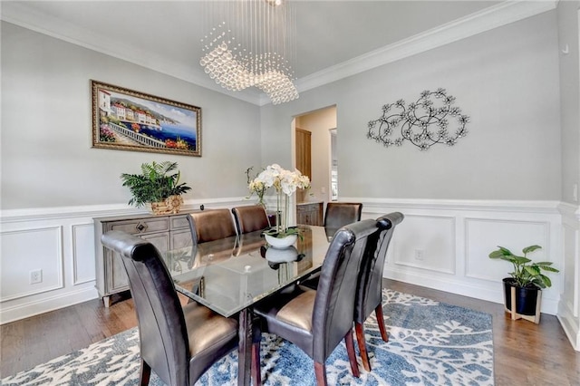 dining space with wood finished floors, a decorative wall, crown molding, and an inviting chandelier