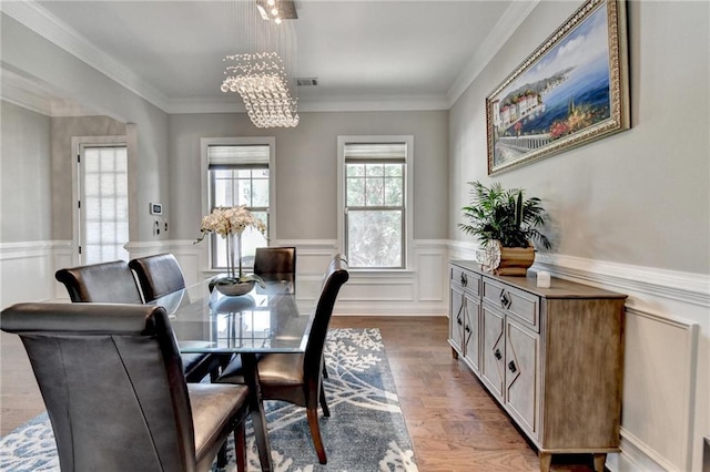 dining space featuring a chandelier, wood finished floors, visible vents, and a wainscoted wall
