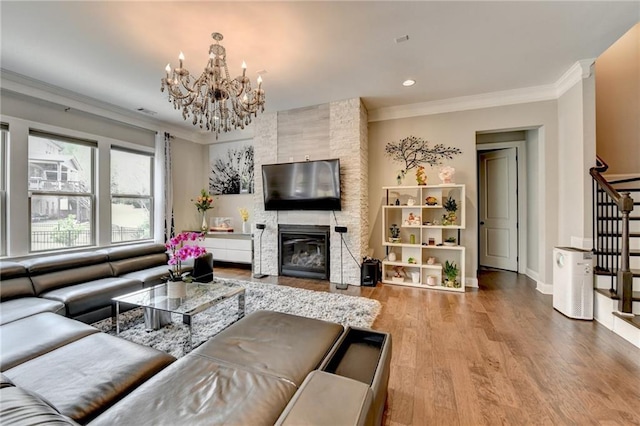 living area with an inviting chandelier, wood finished floors, stairs, crown molding, and a fireplace