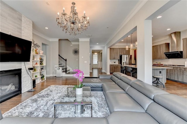 living room with dark wood-style flooring, baseboards, a chandelier, stairs, and crown molding