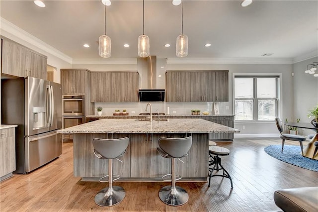 kitchen featuring modern cabinets, appliances with stainless steel finishes, an island with sink, and a breakfast bar