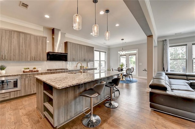 kitchen featuring open shelves, modern cabinets, wall chimney exhaust hood, appliances with stainless steel finishes, and visible vents