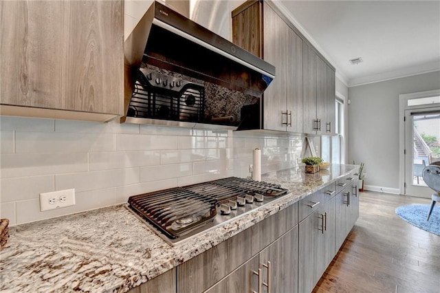 kitchen with stainless steel gas stovetop, extractor fan, light wood-type flooring, crown molding, and tasteful backsplash