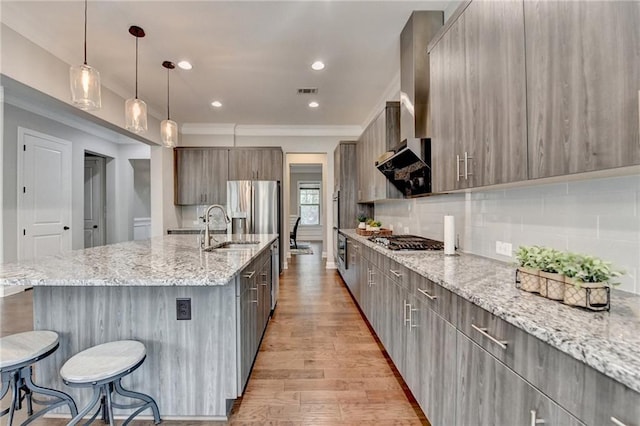 kitchen featuring a kitchen breakfast bar, a sink, a spacious island, modern cabinets, and light wood-style flooring