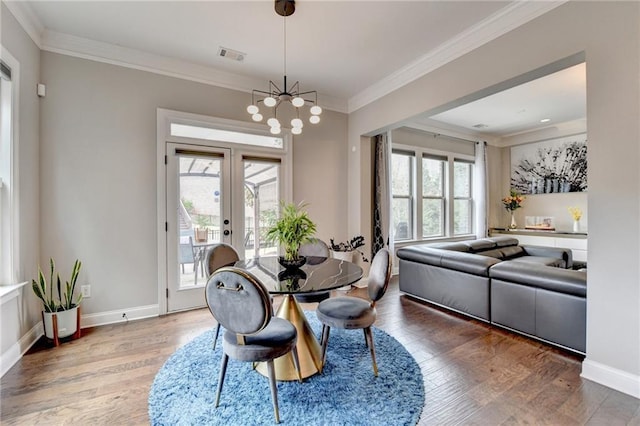 dining space featuring wood finished floors, a chandelier, french doors, ornamental molding, and visible vents