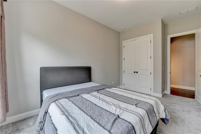 carpeted bedroom featuring baseboards, visible vents, and a closet