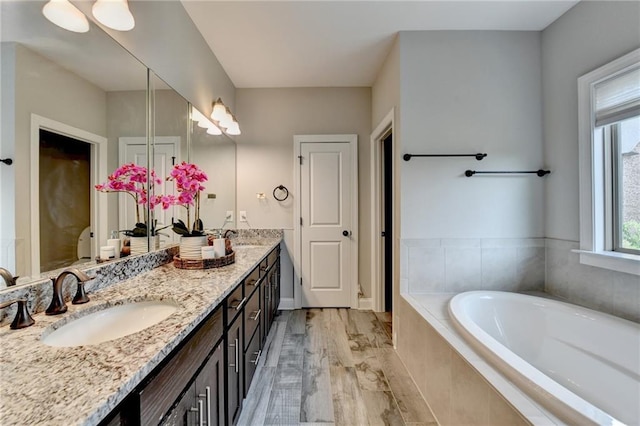 full bath featuring a garden tub, a sink, and double vanity