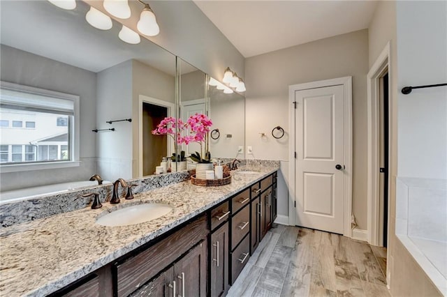 bathroom featuring a tub, a sink, and double vanity