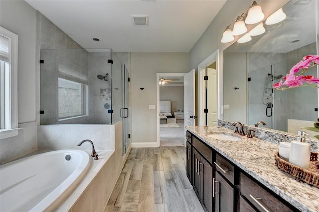 bathroom with a garden tub, vanity, visible vents, and a wealth of natural light