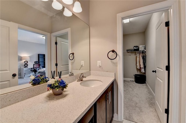 bathroom with baseboards, a spacious closet, and vanity