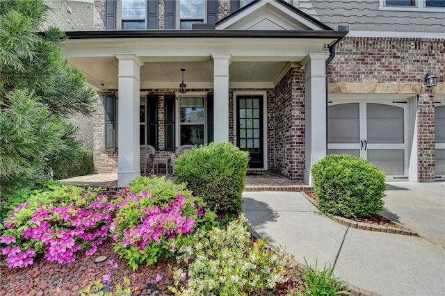 view of exterior entry with covered porch and brick siding