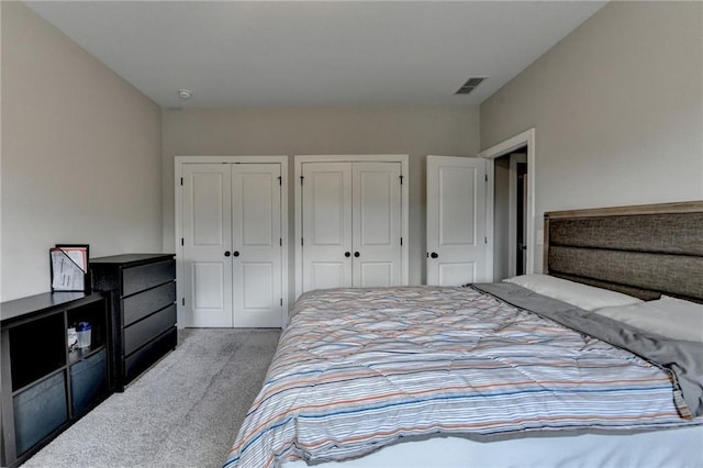 bedroom with carpet floors, multiple closets, and visible vents