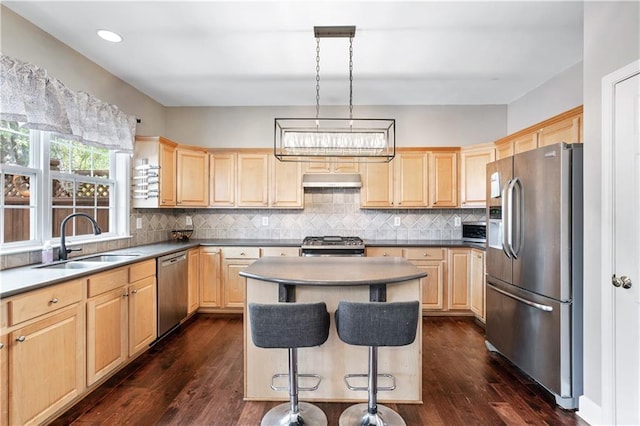 kitchen with dark wood-style floors, stainless steel appliances, light brown cabinetry, a sink, and under cabinet range hood