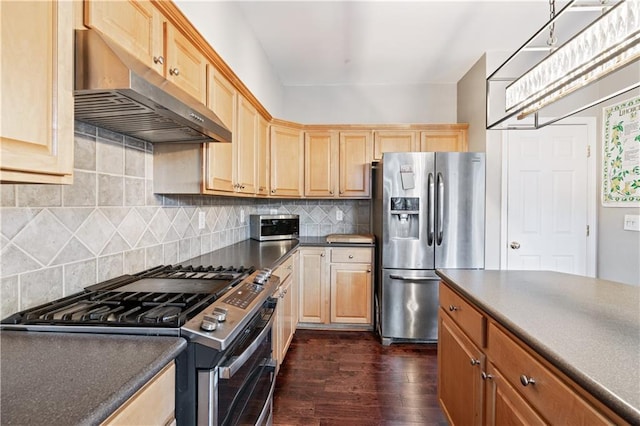 kitchen with dark wood-style floors, stainless steel appliances, dark countertops, tasteful backsplash, and under cabinet range hood