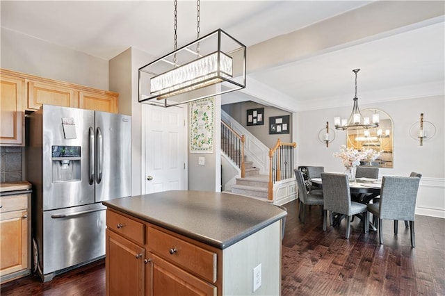 kitchen with decorative light fixtures, stainless steel refrigerator with ice dispenser, dark countertops, dark wood-type flooring, and a kitchen island