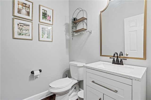 bathroom with baseboards, vanity, and toilet