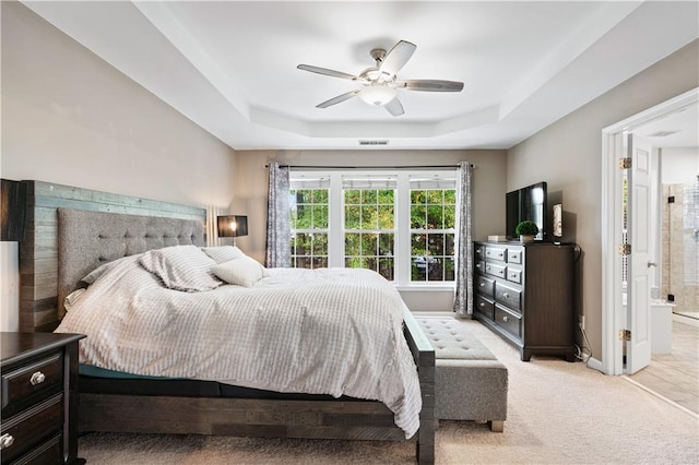 bedroom with ceiling fan, light carpet, visible vents, baseboards, and a raised ceiling